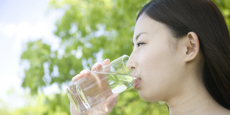 Frau trinkt Wasser aus einem Glas