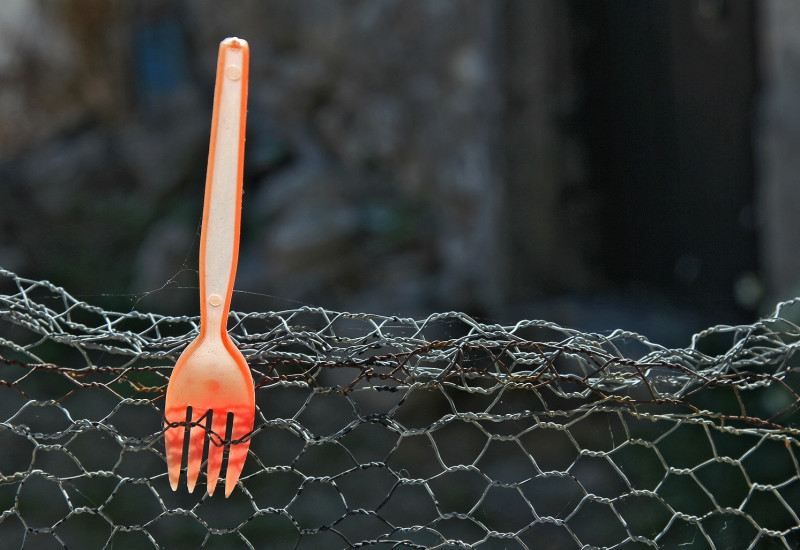auf einem Maschendrahtzaun spießt eine orange Plastikgabel